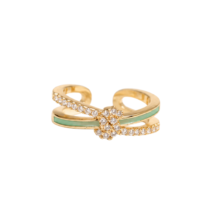 A gold-toned open band ring featuring a central floral cluster of small clear stones and a light green enamel accent stripe, shown on a plain white background.
