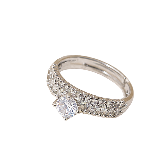 A silver-toned diamond ring with a single round-cut center stone and pavé-set side stones, shown on a plain white background.