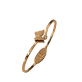A gold-plated bangle bracelet with a small butterfly charm and a tiny clear stone, shown on a plain white background.