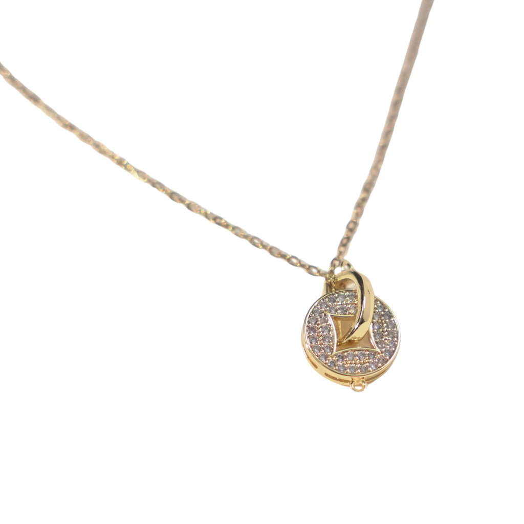 A delicate gold chain necklace featuring a small circular pendant with a central gold heart, set against a plain white background.