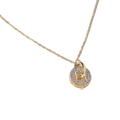 A delicate gold chain necklace featuring a small circular pendant with a central gold heart, set against a plain white background.