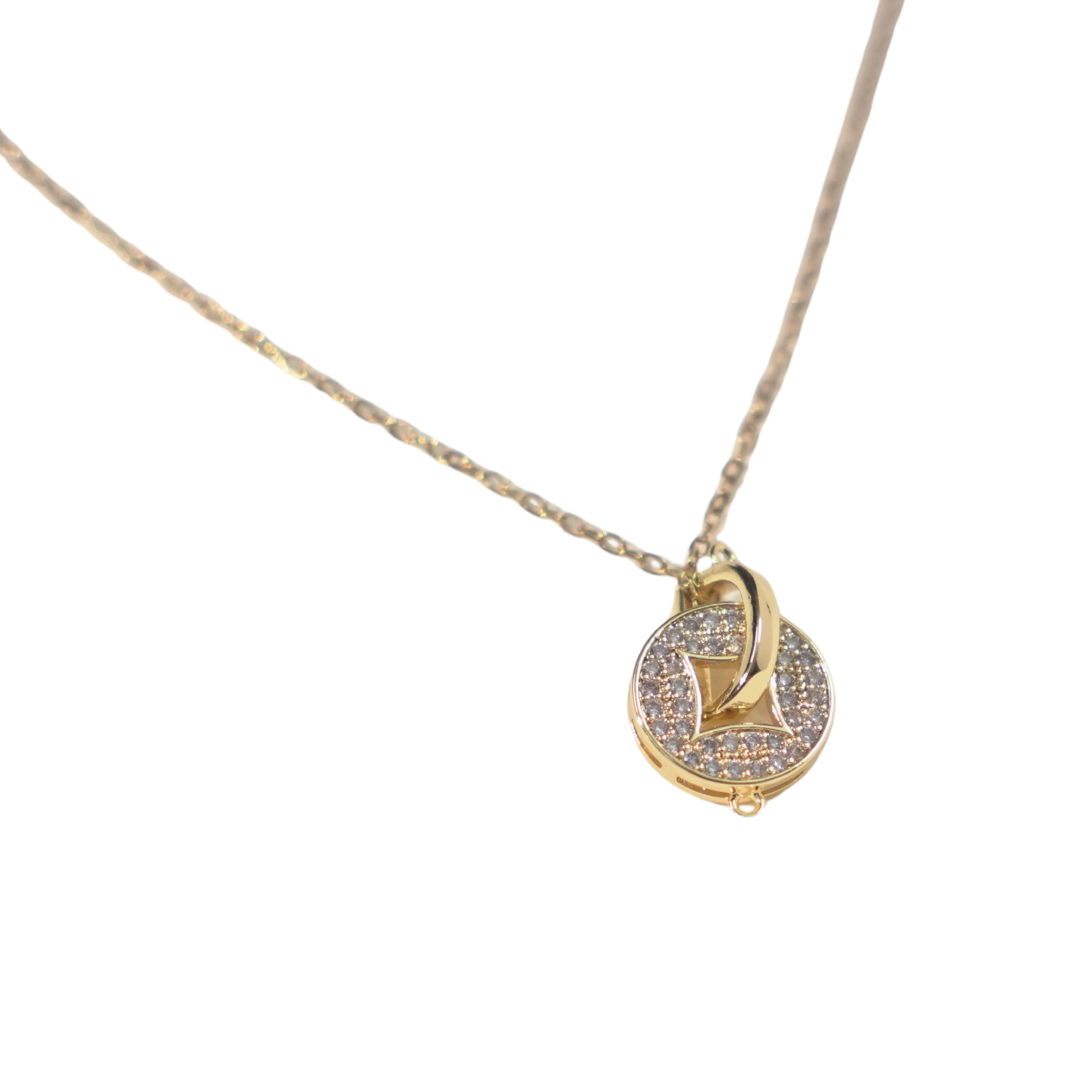 A delicate gold chain necklace featuring a small circular pendant with a central gold heart, set against a plain white background.
