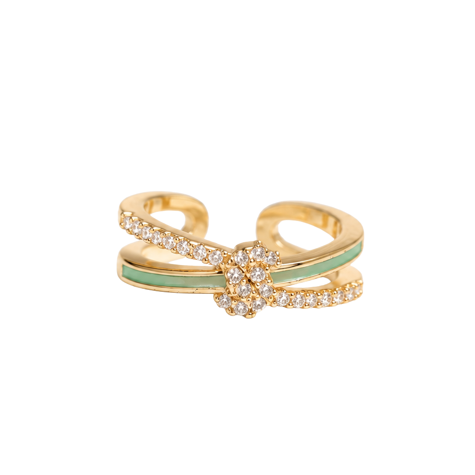 A gold-toned open band ring featuring a central floral cluster of small clear stones and a light green enamel accent stripe, shown on a plain white background.