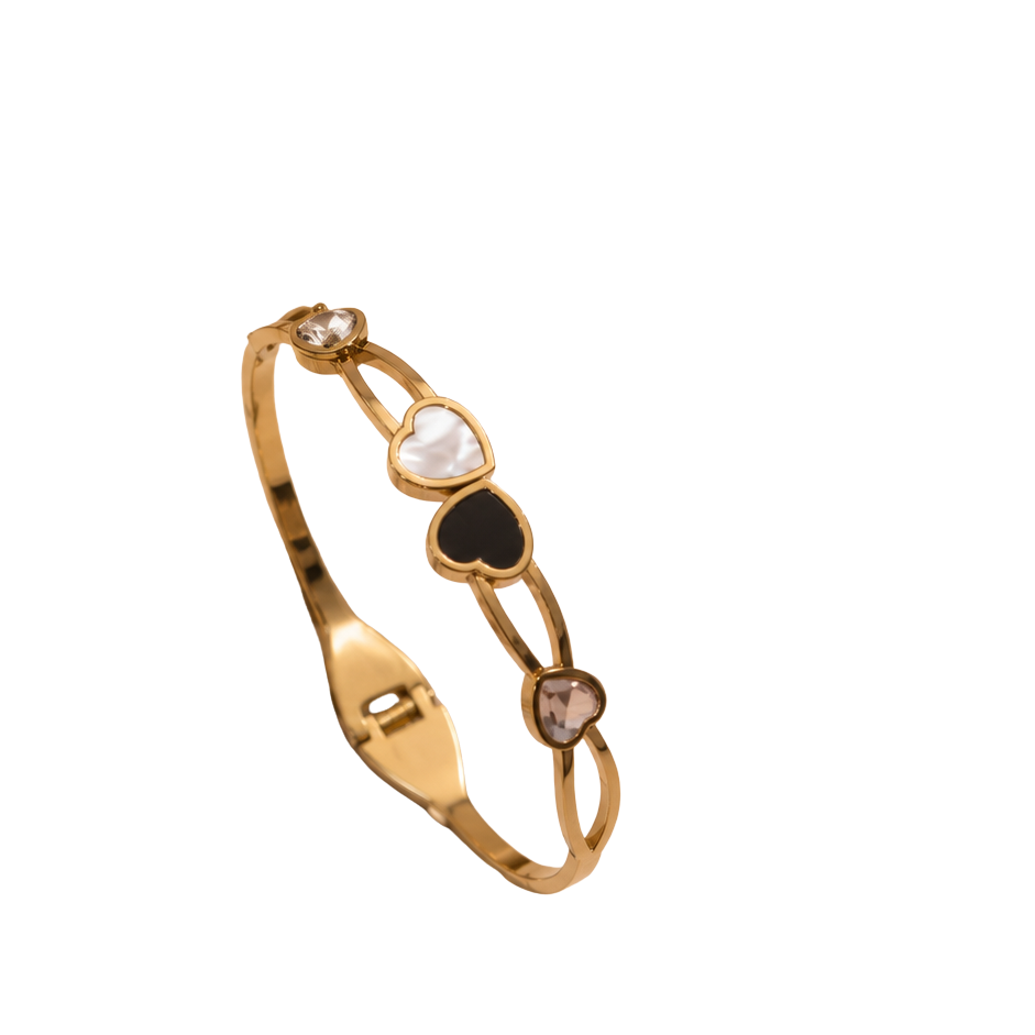 A gold-plated bangle bracelet featuring three heart-shaped inlays in white, black, and brown, with small clear stones at the ends, shown on a plain white background.