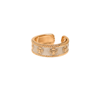 A gold-plated adjustable ring with a white enamel center and embossed starburst details, shown on a plain white background.